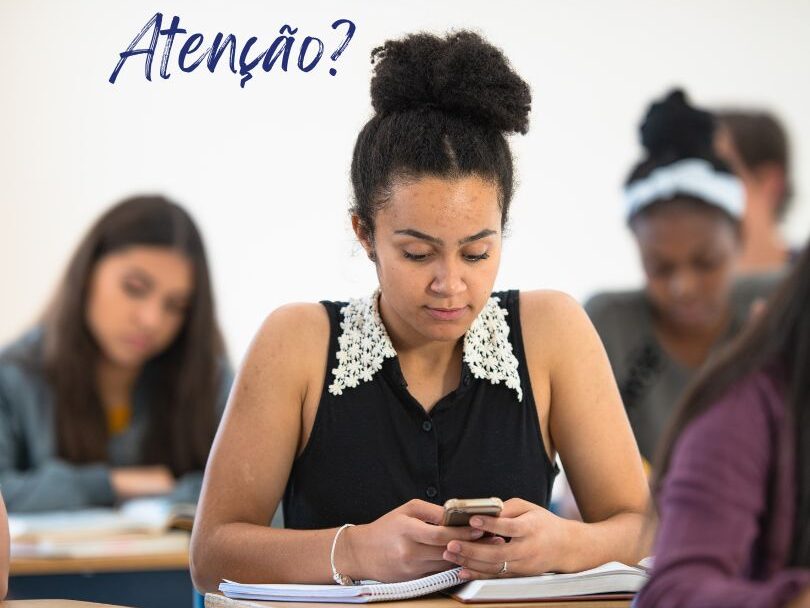 Aluna em contexto de sala de aula distraída ao telemóvel, sem prestar atenção.